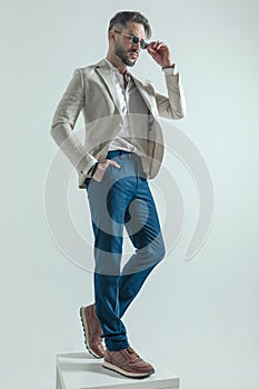 Sexy bearded businessman holding hand in pocket and arranging sunglasses