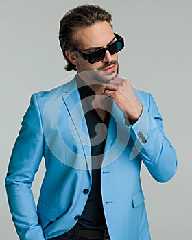sexy bearded businessman with sunglasses holding hands in pockets and looking to side