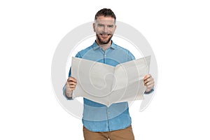 Sexy bearded guy in his forties holding newspaper and smiling