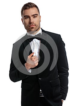 Sexy bearded man in black tuxedo holding hand in pocket