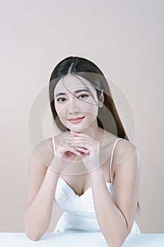 Sexy beautiful Asian woman in white dress with natural makeup and looking at camera isolated over white background. Fashion shiny