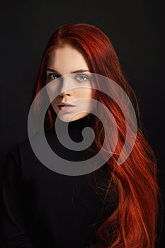 beautiful redhead girl with long hair. Perfect woman portrait on black background. Gorgeous hair and deep eyes Natural beauty