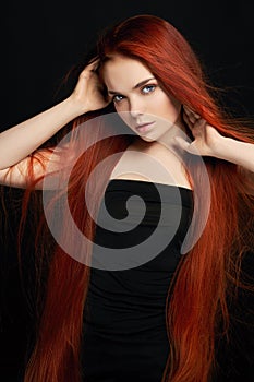 beautiful redhead girl with long hair. Perfect woman portrait on black background. Gorgeous hair and deep eyes Natural beauty