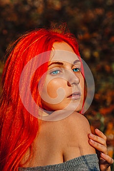 Sexy beautiful redhead girl with long, strong and thick hair. Perfect woman portrait on a background of autumn foliage. Gorgeous