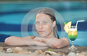 Beautiful woman relaxing in the pool with a cocktail