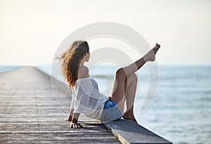beautiful woman relaxing on pier with sea view
