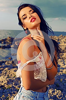 beautiful woman wears a top with jeans shorts and posing beach