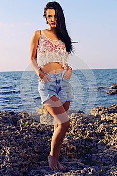 beautiful woman wears a top with jeans shorts and posing beach