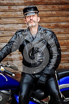 Sexy biker dressed in black leather sitting on his bike