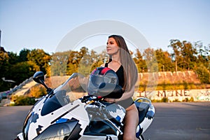 Sexy biker fitness girl with perfect slim body on motorbike posing in street.