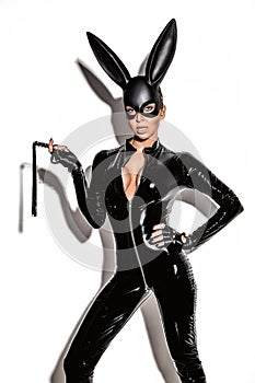 Sexy blonde beautiful woman posing in latex costume and black bunny mask on white background.