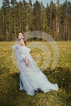 Sexy blonde in a chic classic dress posing in nature