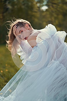 Sexy blonde in a chic classic dress posing in nature