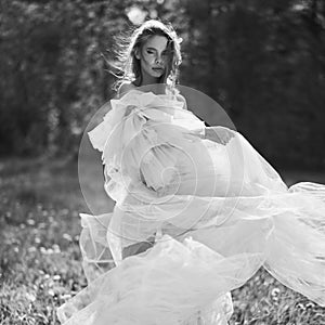 Sexy blonde in a chic classic dress posing in nature