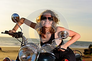 Sexy blonde woman in sunglasses smiling and grimacing while sitting on the motorbike. Bright emotions on vacation