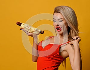 Sexy blonde woman winks seductively looking at the camera and holding fast food.