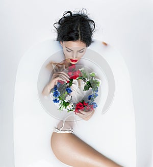 brunette model in milk bath with the crown from flowers