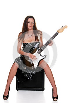 brunette sitting on an amplifier with guitar