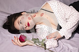 Sexy brunette woman with kisses, lipstick marks on her face and neck, with red rose. girlfriend, date, relashionship. lesbian gay