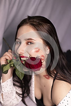 Sexy brunette woman with kisses, lipstick marks on her face and neck, with red rose. girlfriend, date, relashionship. lesbian gay