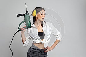 Sexy Builder girl holding a drill. concept of advertising Housewives, work tools and construction-related works