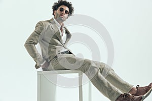 Sexy businessman with curly hair adjusting suit while sitting