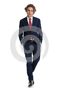 Sexy businessman in elegant suit walking with hands in pockets