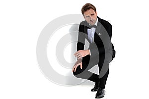 Sexy businessman squatting, resting his arms on his lap