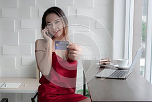 Sexy businesswoman Wearing a red dress. Sitting by the window. Inside the living room There are notebooks and snacks on the table