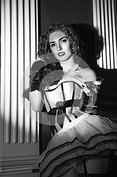 cabaret woman in corset posing in vintage armchair. Burlesque lingerie in fashion interior. black and white