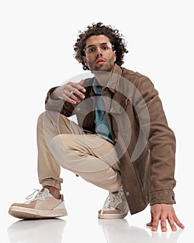 sexy casual guy with glasses crouching and posing in a cool way