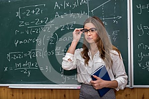 Sexy caucasian female teacher against blackboard with mathematical formulas in classroom