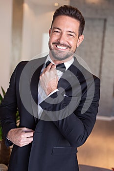 Sexy celebrity man adjusting tuxedo indoors