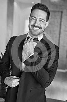 Sexy celebrity man adjusting tuxedo indoors black and white