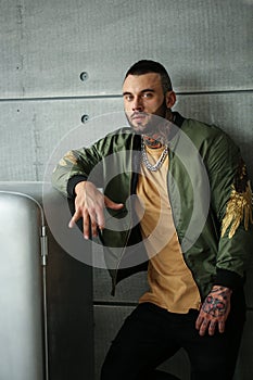 closeup portrait of elegant handsome male model with fashion tattoo and a black beard standing and posing near Stylish old re