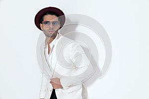 sexy cool man with hat and sunglasses unbuttoning white jacket suit