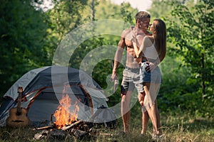 Sexy couple camping near forest background. Nature and lifestyle concept. Romantic lovers at countryside.