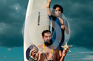 Sexy couple holding surfboard. Surfer couple on sky. Friendship, sea, summer vacation, water sport. Happy couple surfers