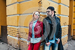 Sexy couple in leather jacket and sunglasses posing over wall in city