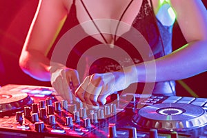 Sexy disc jockey on turntable playing in nightclub. DJ mixing audio in night club