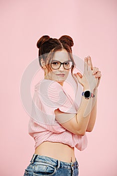 Sexy eccentric lady making gun gesture, playing a spy. Over pink background.