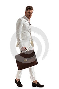 Sexy elegant businessman wearing white suit and holding suitcase