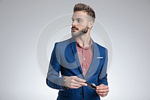 Sexy elegant man in blue suit holding sunglasses