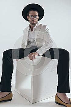 sexy fashion man wearing hat and glasses and posing in a cool way