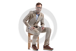 Sexy fashion model sitting on a chair, resting his hands