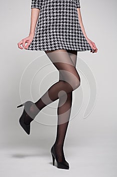 Sexy female legs in black tights and shoes in studio on a white background