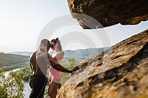 fit mixed race couple with perfect bodies in sportswear posing on the rocky mountains landscape