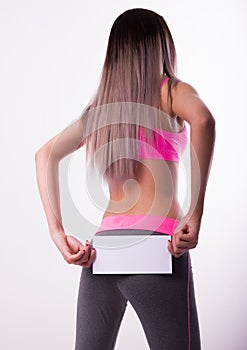 fitnes brunette in a tracksuit holding empty white board