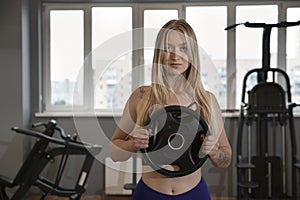 Sexy fitness model posing in the gym. Blonde girl is holding dumbbells. Sport, healthy lifestyle