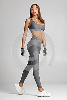 Sexy fitness woman. Beautiful athletic girl on the gray background photo
